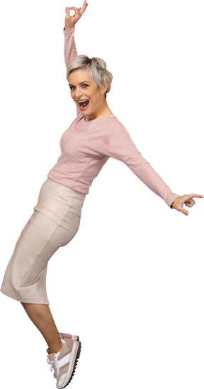 Vista lateral de una mujer feliz en ropa casual de pie sobre los dedos del pie
