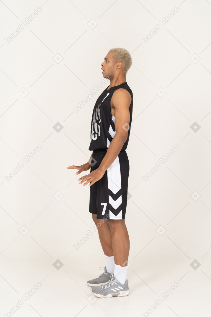 Vista lateral de un joven jugador de baloncesto masculino perplejo