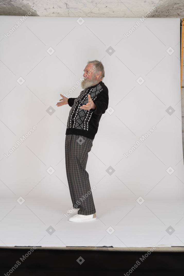 Side view of cheerful elderly man standing with open arms