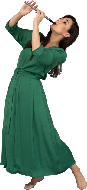 後ろに寄りかかってフルートを演奏する緑のドレスを着た若い女性の4分の3のビュー