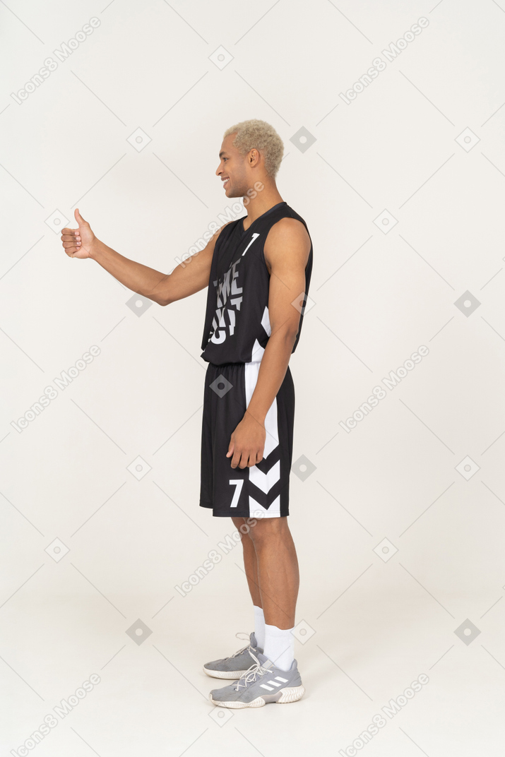 엄지손가락을 보여주는 젊은 남자 농구 선수의 측면 보기