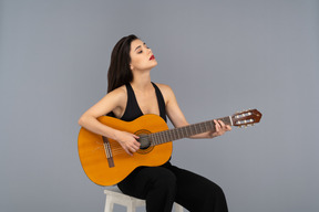 魅力的な若い女性はギターを弾く