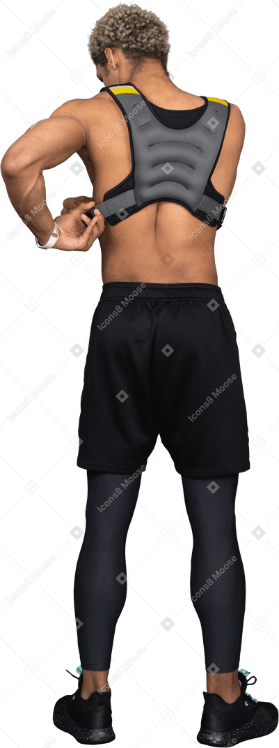 Vista traseira de um homem afro sem camisa ajustando o colete