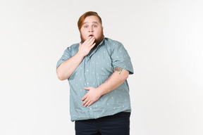 Shocked young overweight man touching his face