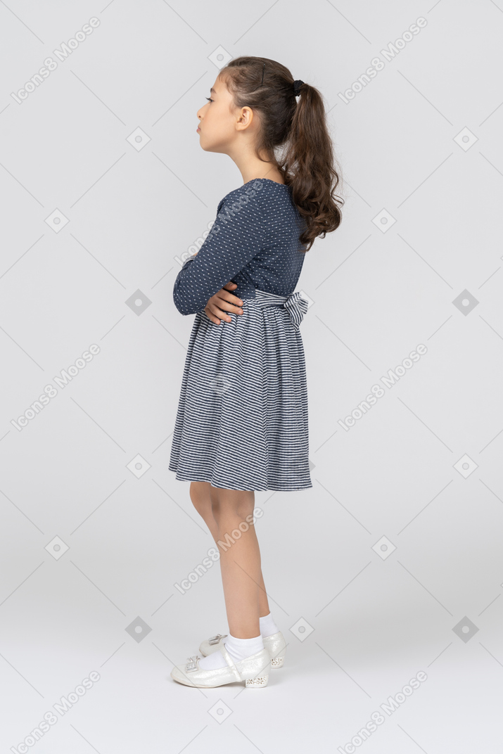 Vista lateral de uma menina dobrando as mãos e fazendo beicinho