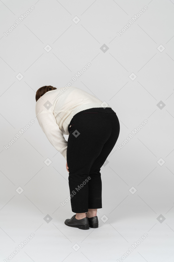 Retrovisor de uma mulher rechonchuda de suéter branco, curvando-se