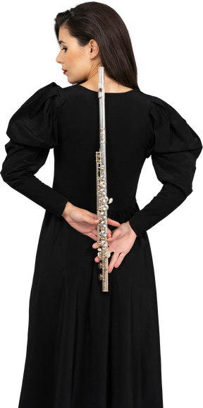 Vista traseira de uma jovem de vestido preto segurando uma flauta atrás