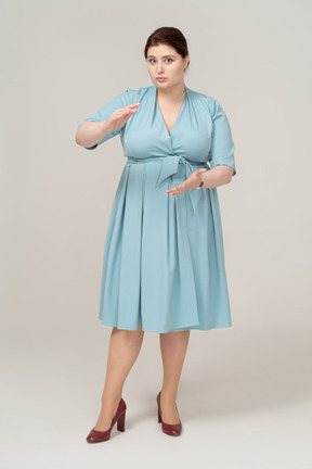 Vista frontal de uma mulher de vestido azul mostrando o tamanho de algo