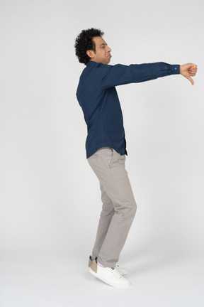 Vista lateral de um homem com roupas casuais mostrando o polegar para baixo