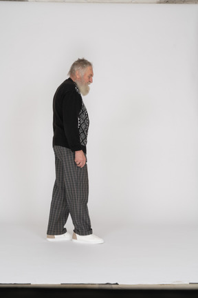 Vista laterale di un uomo anziano che cammina e guarda in basso