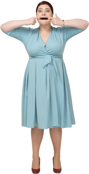 Front view of a woman in blue dress touching mouth