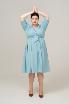 頭上に手をポーズでポーズをとって青いドレスを着た女性の正面図