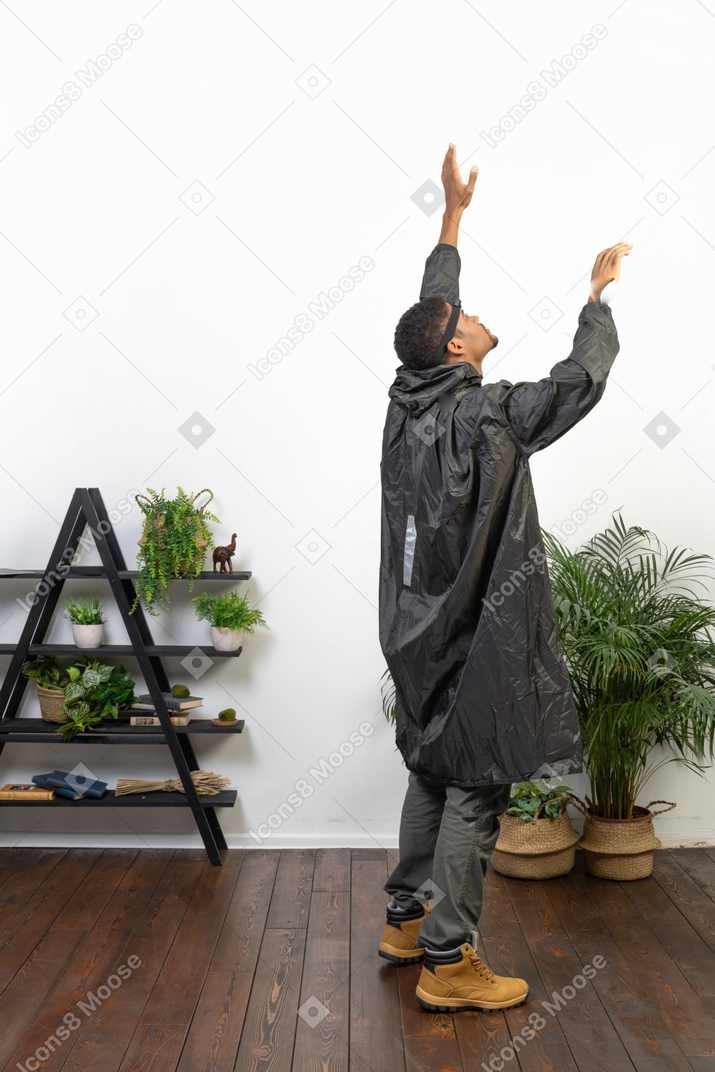 Rückansicht eines mannes im regenmantel mit erhobenen armen
