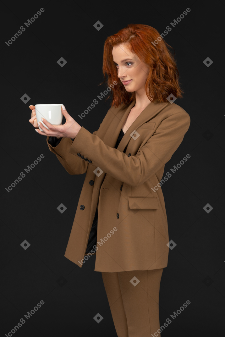 Mulher sorridente de terno segurando uma caneca de café