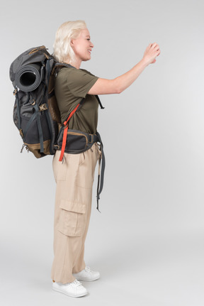 Mature female tourist carrying heavy backpack and making photos with smartphone