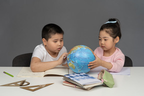 Menino e menina olhando para um globo de mesa