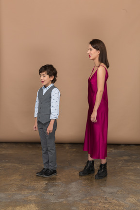 Disgusted woman in red dress and boy standing in profile