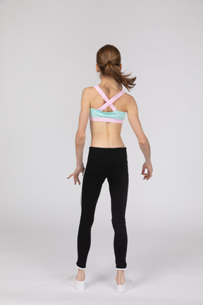 Vista posterior de una jovencita en ropa deportiva inclinando los hombros
