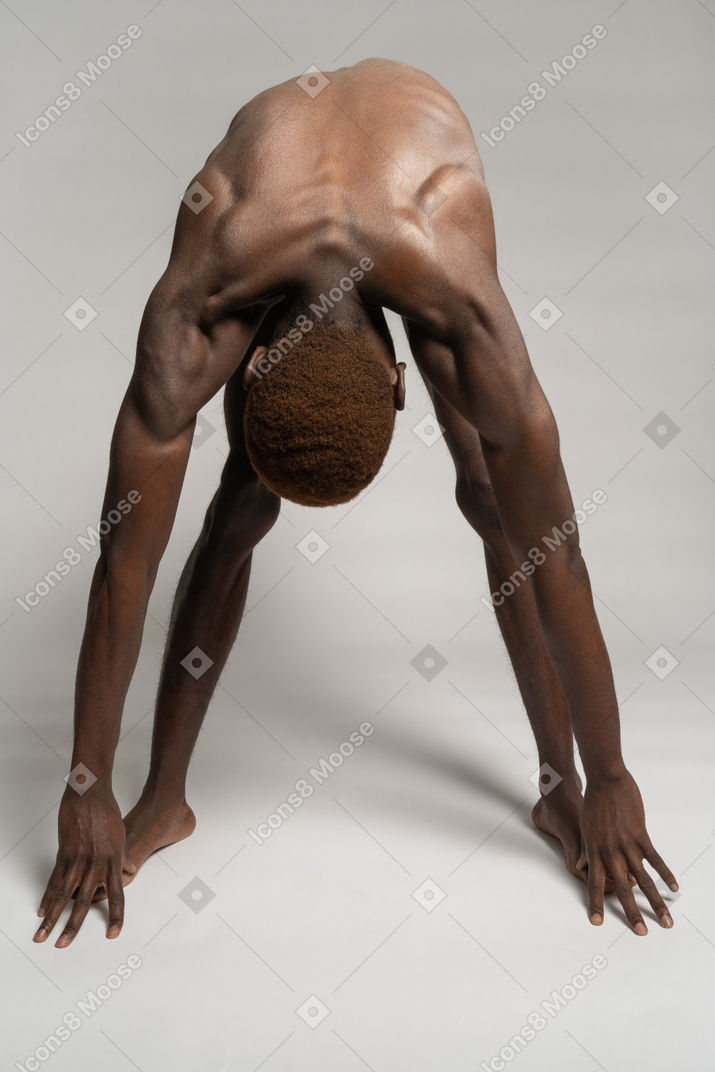 Naked man bending and reaching his toes