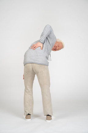 Back view of man bending over and holding his hand on his lower back