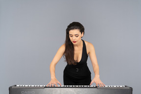 Vue de face d'une jeune femme en robe noire jouant du piano