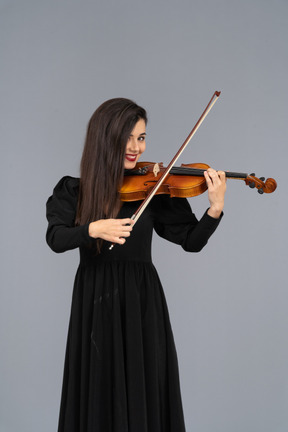 バイオリンを弾く黒いドレスを着た若い女性のクローズアップ