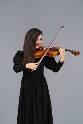 Close-up de uma jovem de vestido preto tocando violino