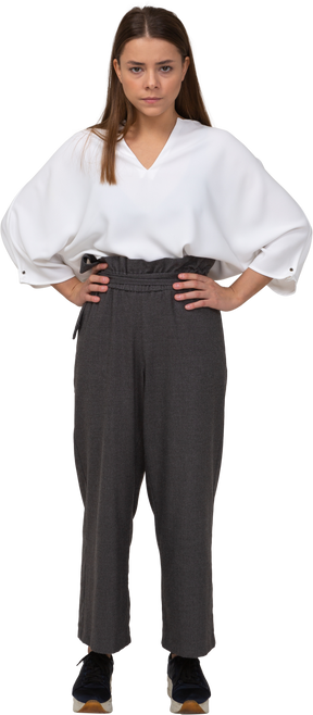Front view of a serious young lady in office clothing putting hands on hips