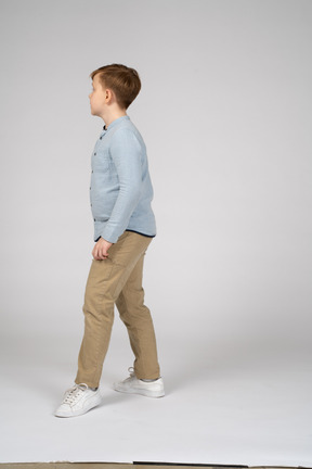 Vista lateral de um menino de camisa azul dando um passo à frente