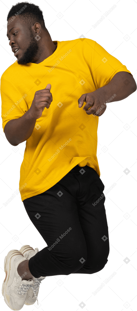 黄色のtシャツを着てジャンプする若い浅黒い肌の男の正面図