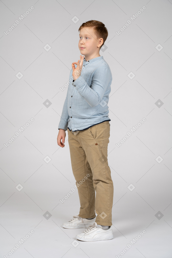 Vista lateral de um menino mostrando sinal de ok