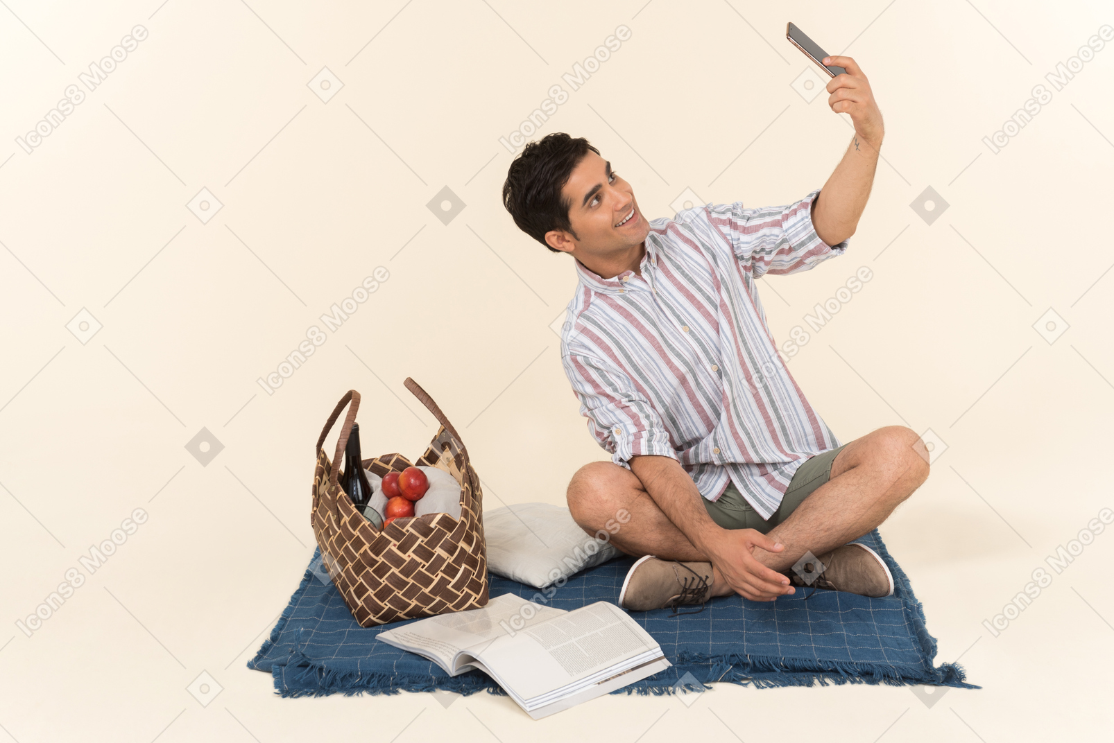 Молодой кавказский парень сидит на одеяле и делает селфи