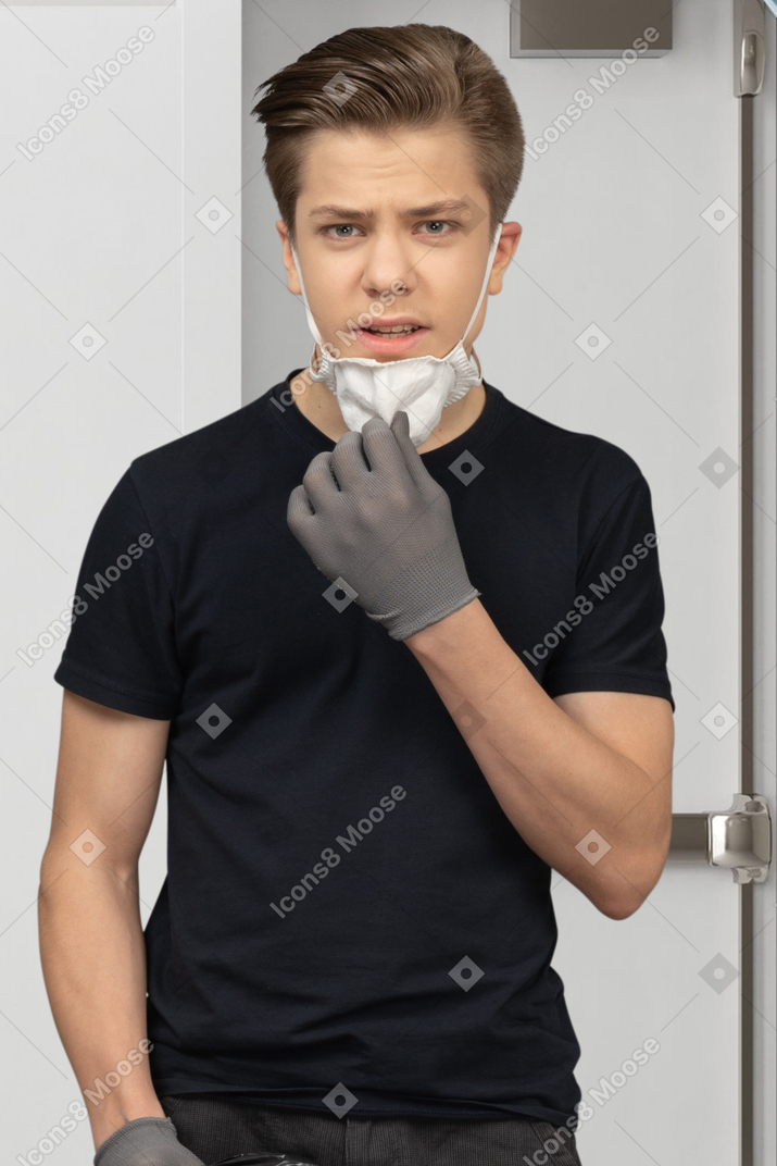 Um rapaz irritado com sua máscara médica