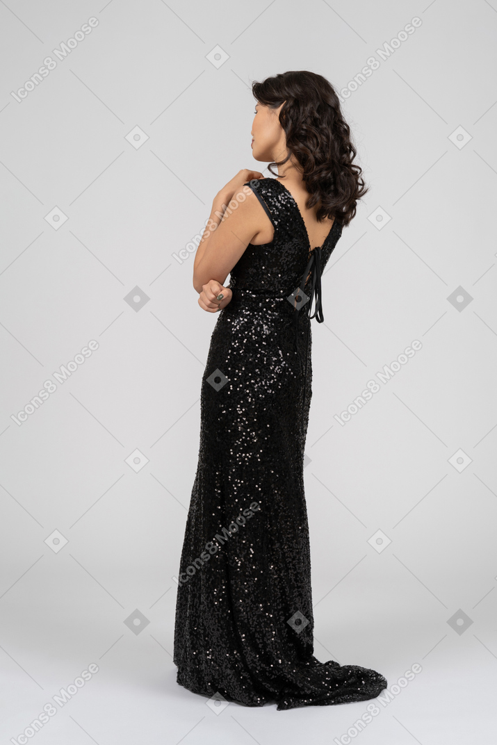 Mujer en vestido de noche negro de pie a la cámara