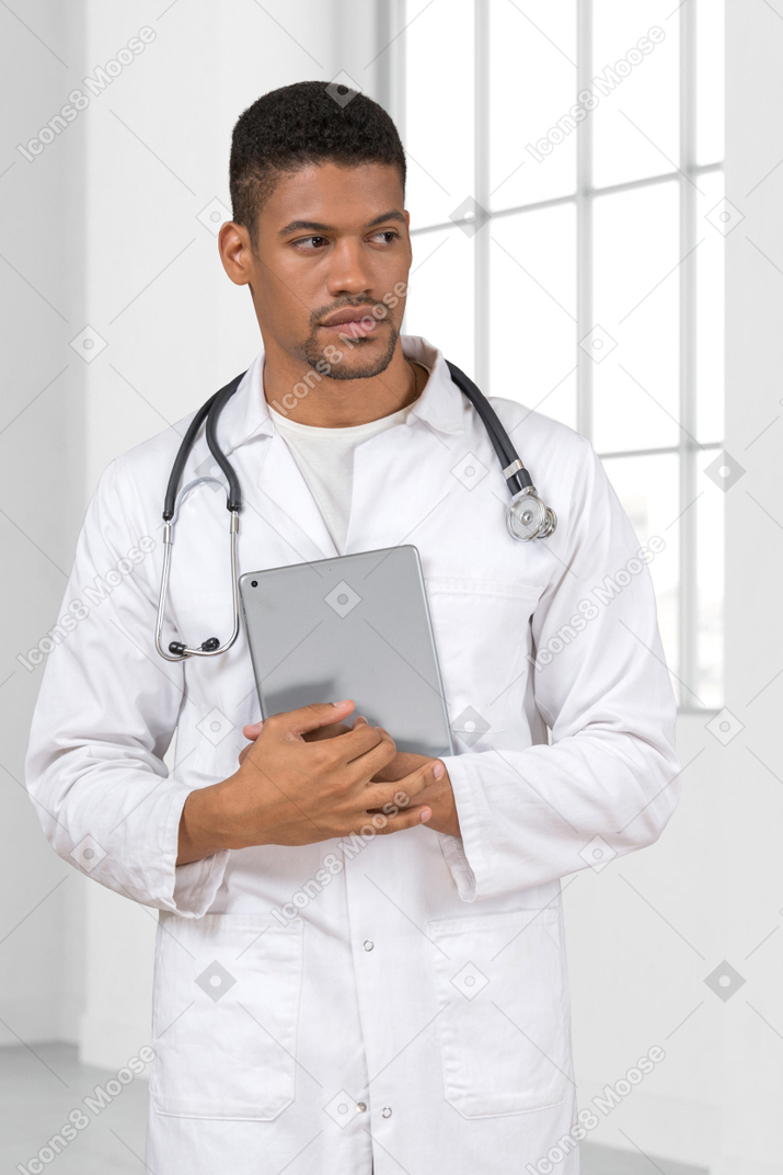 Mann arzt hält eine tablette und schaut weg