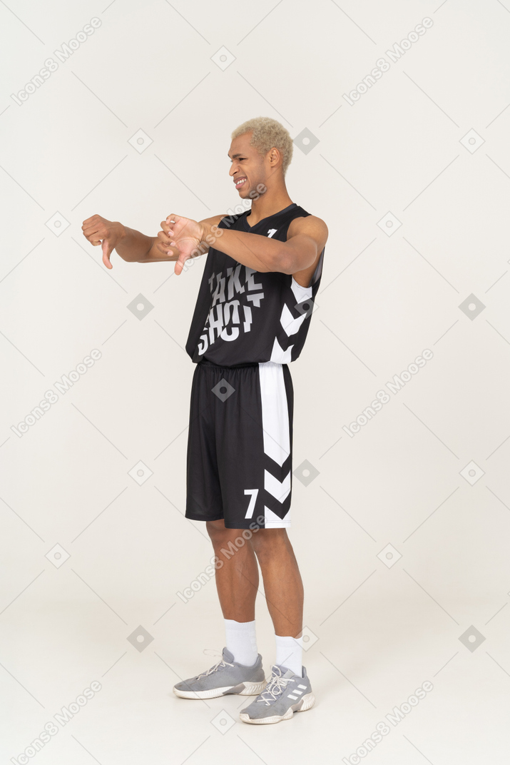 Vista de tres cuartos de un joven jugador de baloncesto masculino mostrando los pulgares hacia abajo