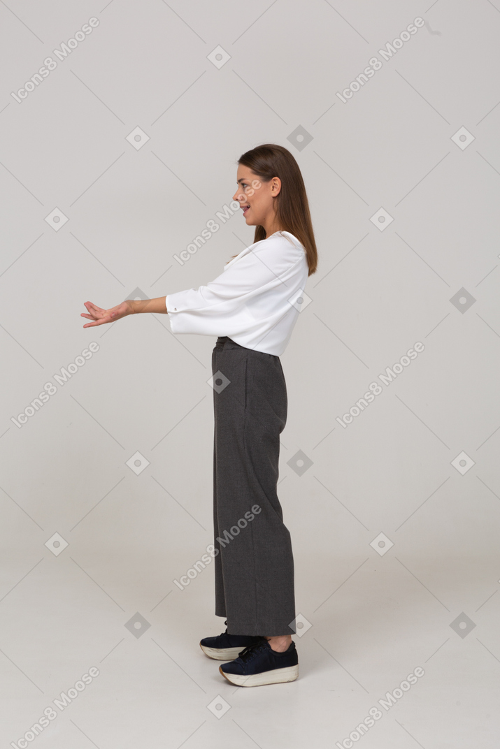 Вид сбоку молодой леди в офисной одежде, протягивающей руки
