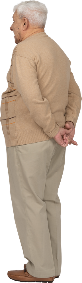 Vista trasera de un anciano con ropa informal de pie con las manos detrás de la espalda