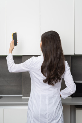 Женщина-врач, использующая свой телефон, вид сзади