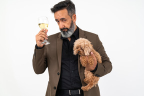 ワインのガラスを保持している子犬を持つハンサムな男