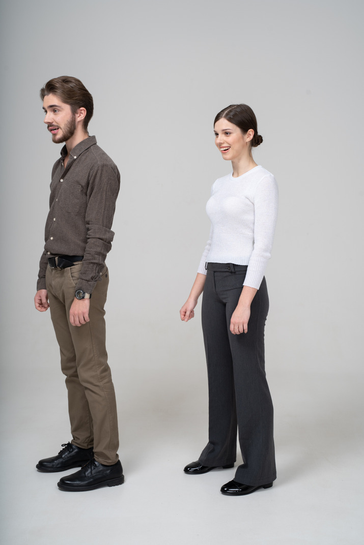 Three-quarter view of a smiling young couple in office clothing biting lips