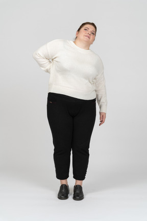 Mulher plus size com roupas casuais, sofrendo de dores na parte inferior das costas