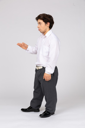 Profile view of a young office worker holding out his hand
