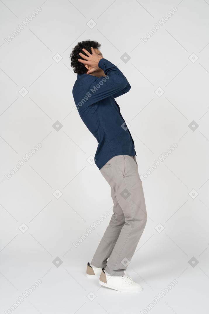 Side view of a man in casual clothes touching head