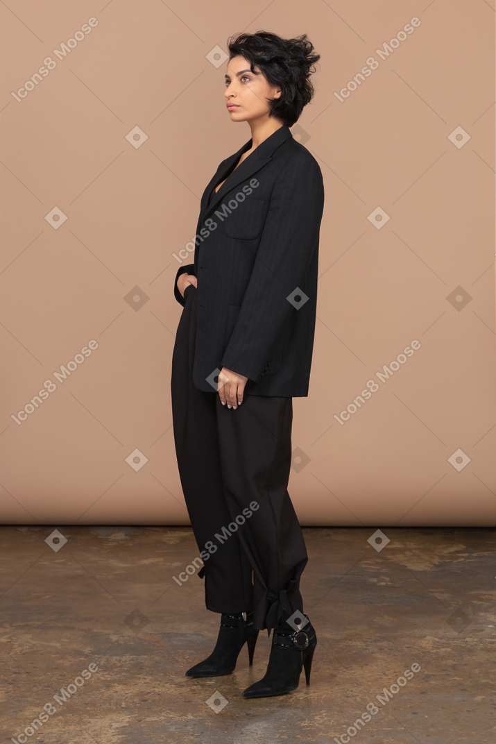 Вид в три четверти деловой женщины в черном костюме, смотрящей вверх