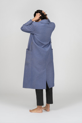 Back view of a woman in coat pulling her hair