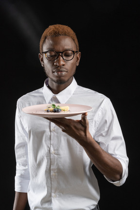 Close-up a waiter looking  intently at the dish in the dark