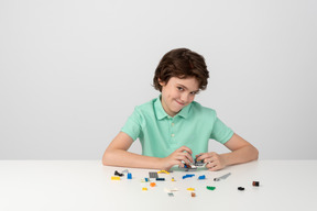Cute boy in green polo shirt playing with building blocks