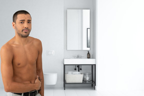 A man without a shirt standing in a bathroom