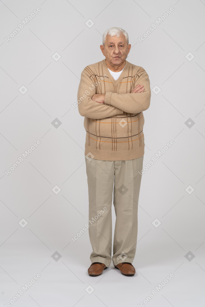 Front view of an old man in casual clothes standing with crossed arms